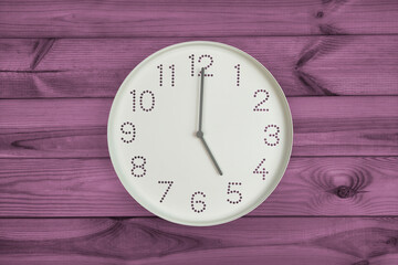 Five o'clock. Time management or business concept. Plain white wall clock showing 5 pm on a wooden background. End of working day. Opening or closing hours. Schedule or working, study hours.