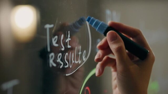 Project. A team member actively writes on a glass whiteboard in a meeting room. Cinematic tracking shot of experienced worker planning business strategy creating strategy studying, planning