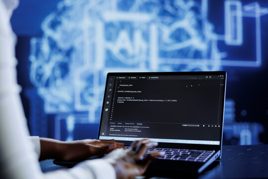 Qualified technician updates neural networks made up of interconnected nodes, writing intricate binary code scripts on laptop. Skilled expert uses programming to upgrade AI simulation model