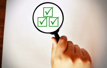Magnifying Glass showing three correct sign symbols are on a white background. Space for text....