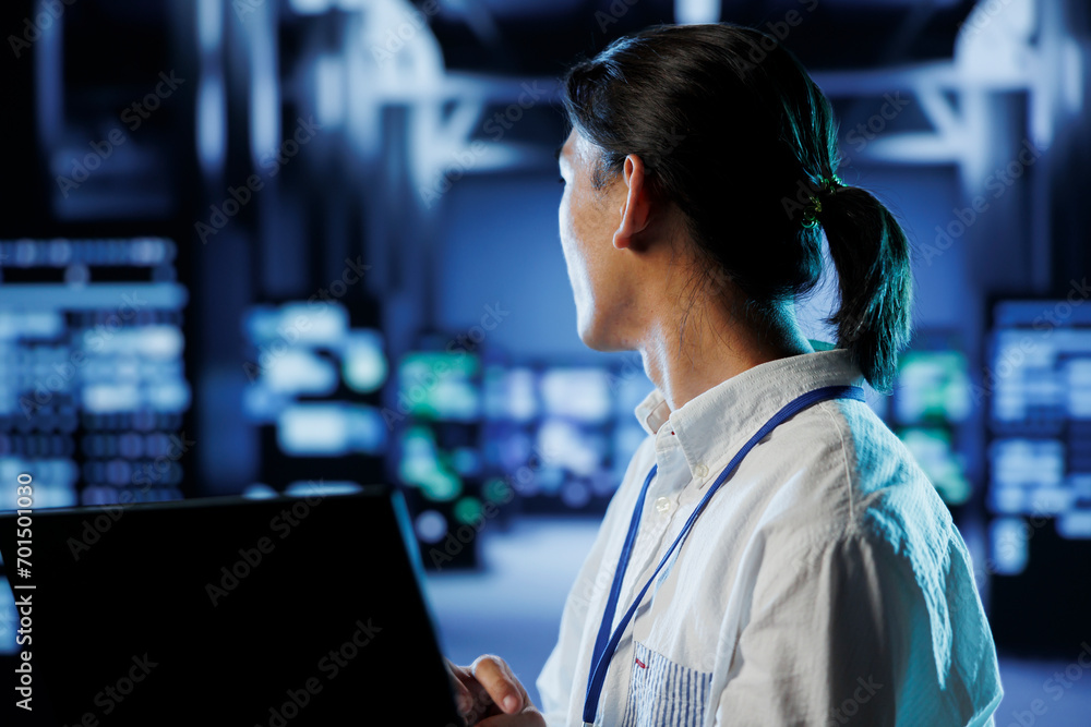 Poster system administrator in data center uses laptop to prevent system overload during peak traffic perio