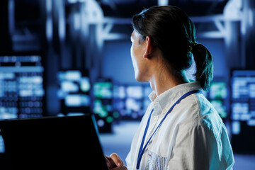 System administrator in data center uses laptop to prevent system overload during peak traffic...