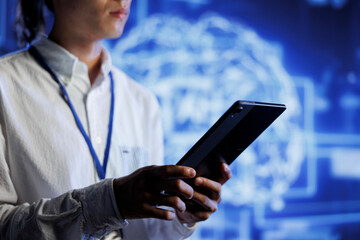 Admin using tablet in server room to maintenance artificial intelligence neural networks simulating human thought processes. High tech establishment worker does checkup on AI systems
