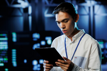 Tech support worker between server room equipment providing processing resources for businesses worldwide. Skillful developer fixes data center supercomputers used for managing massive databases