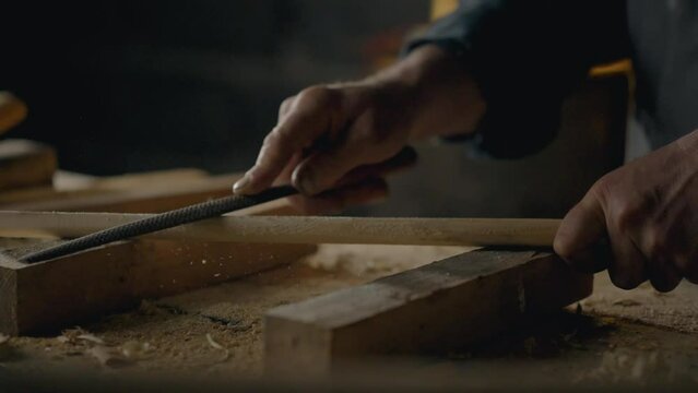 Professional carpenter Uses hand tool rasp In workshop workshop Young expert Works with wood blanks In production room, work. Carpenter working with wood preparing for processing
