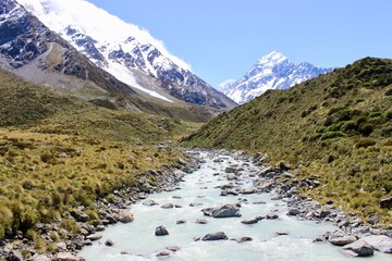 New Zealand river and mountains in the back with snow green gras