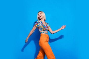 Profile portrait of lovely positive girl walking look empty space advert isolated on blue color background