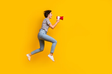 Full size profile portrait of astonished girl hold communicate toa loudspeaker jump run empty space isolated on yellow color background - obrazy, fototapety, plakaty