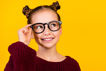 Portrait of small clever charming girl arm touch eyewear beaming smile look empty space isolated on...