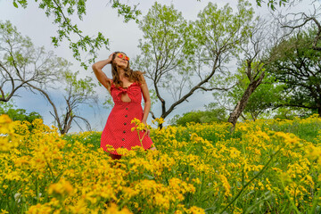 Obraz na płótnie Canvas A Lovely Brunette Model Poses In A Field Of Yellow Flowers In A Texas Prarie