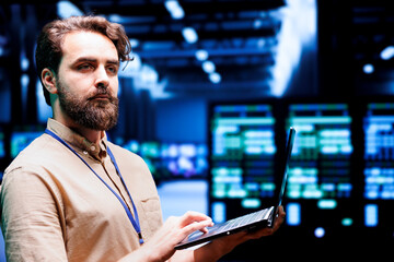 Fototapeta premium Expert IT programmer using laptop to assess supercomputer cybersecurity dangers arising due to unsecured network connections. Supervisor ensuring high tech facility is impenetrable by malware attacks