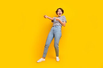 Fototapeta premium Full size portrait of astonished girl arms pull empty space rope string isolated on yellow color background