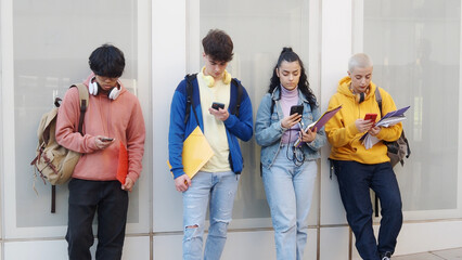 Four young diverse teenage students looking at smartphone on a campus