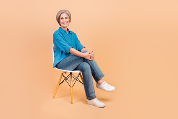 Full size photo of optimistic nice cheerful woman dressed stylish shirt sit on chair legs crossed...