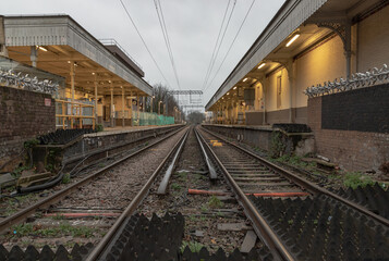 Fototapeta na wymiar Perspective view on empty railway tracks and electric infrastructure equipment, wires at Acton central rail station. The Railway system with Metal frames of Train platform, Transport and shipping land