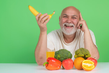 Obraz premium Senior drink near fruits and vegetables in studio. Elderly man on fruits and vegetables diet. Vegetables and Healthy Fruit for aged people. Healthy lifestyle. Aged Fruit Vegetables Dieting.