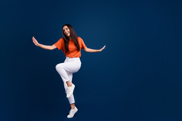 Fototapeta na wymiar Full length photo of sweet pretty woman dressed orange t-shirt having fun discotheque empty space isolated dark blue color background