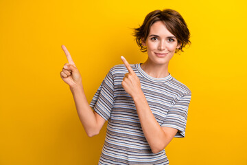 Photo of good mood woman with bob hairdo dressed striped t-shirt indicating at sale empty space isolated on yellow color background