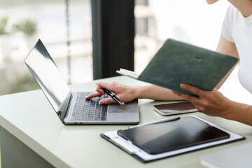 Caucasian university woman in an online class lecture, wearing headphones, smiling, and taking notes in a planner.
