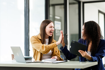 Caucasian and an African American university woman giving a high-five, celebrating a successful project collaboration.