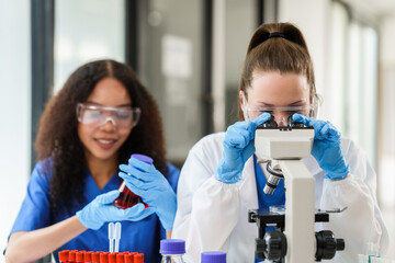 African American and a Caucasian researcher conducting a blood lab test, examining samples with a...