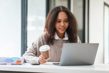 African American university student with a coffee cup, engaged in her studies or working on her MBA...