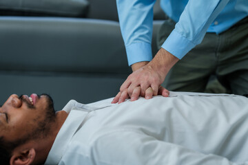 Close up man lying down while another individual, likely a medical professional, is performing a CPR chest compression, potentially in response to heart attack.