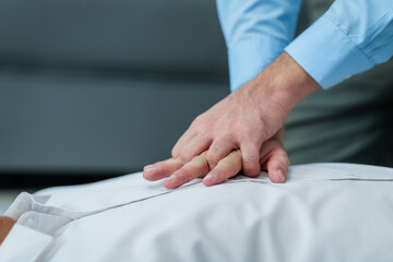 Close up man lying down while another individual, likely a medical professional, is performing a CPR chest compression, potentially in response to heart attack.