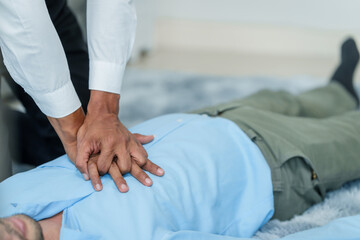 Close up man lying down while another individual, likely a medical professional, is performing a CPR chest compression, potentially in response to heart attack.