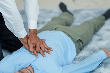 Tuinposter Close up man lying down while another individual, likely a medical professional, is performing a CPR chest compression, potentially in response to heart attack. © Ratirath