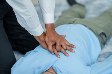 Close up man lying down while another individual, likely a medical professional, is performing a CPR chest compression, potentially in response to heart attack.