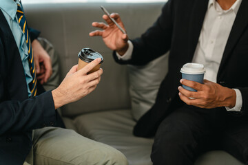 Two men in professional attire on sofa, discussing business matters such as investments or legal...