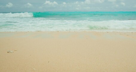 Turquoise sea waves on golden sand. Ocean water and smooth beach background.