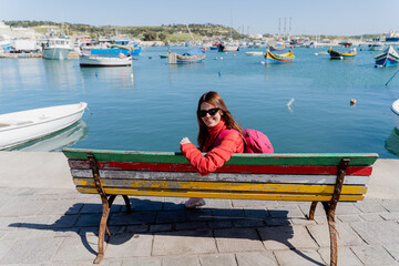A girl sits by the sea in a small village in Malta.