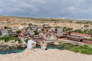 Malta. A guy and a girl are sitting on a cliff with a beautiful view. - obrazy, fototapety, plakaty
