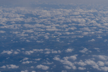 The plane flies in the sky with clouds. Overall plan.