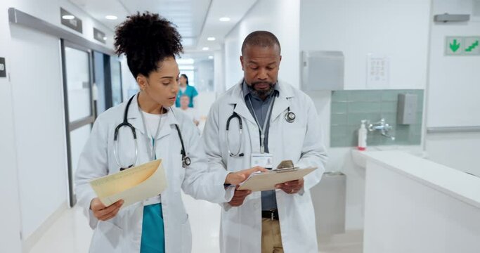 Healthcare, discussion and team of doctors in a hospital with clipboard for information. Conversation, documents and medical workers walking and talking for treatment plan in medicare clinic corridor