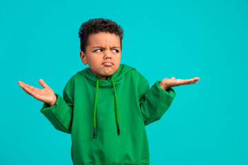 Photo of confused funny schoolboy with wavy hair dressed green pullover look empty space shrug...