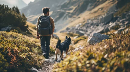 Photo sur Plexiglas Beige A man and a dog hiking in beautiful mountain landscape, man with tourist backpack hiking on spring wild field together with a dog. The concept of the campaign, hiking , spring traveling and nature.