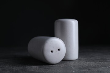Salt and pepper shakers on dark textured table