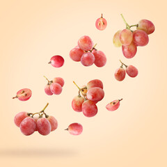 Fresh grapes in air on light orange background