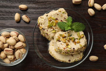 Tasty halva with pistachios and mint on wooden table, flat lay