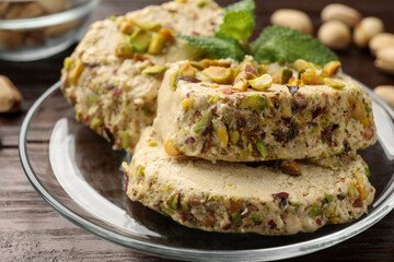 Tasty halva with pistachios and mint on wooden table, closeup