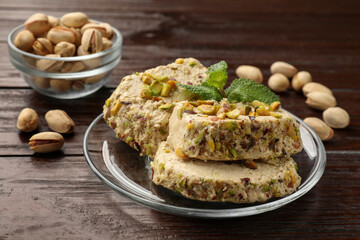 Tasty halva with pistachios and mint on wooden table, closeup
