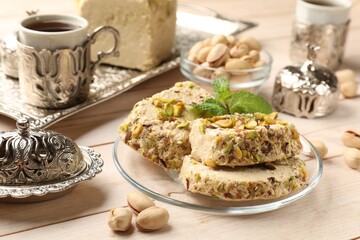 Tasty halva with pistachios and mint served on wooden table