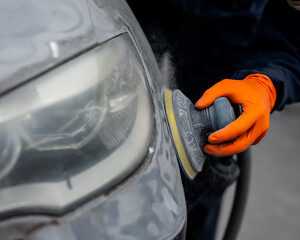 A mechanic sands the putty on a car body with a machine. Repair after an accident. 