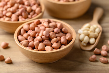 Peanut in bowl with spoon on wooden background