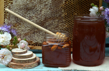 Still life with natural honey in jar, dipper, flowers and stick on wooden background outside....