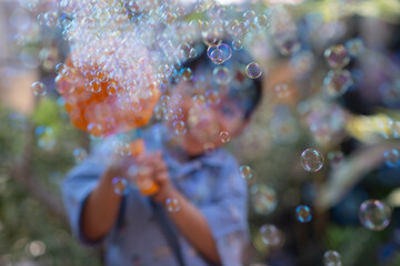 the blur photo of the boy playing bubble machine gun in the garden