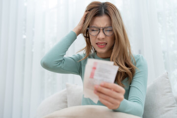 Her posture and facial expression convey a sense of worry, as she grapples with the financial burden.